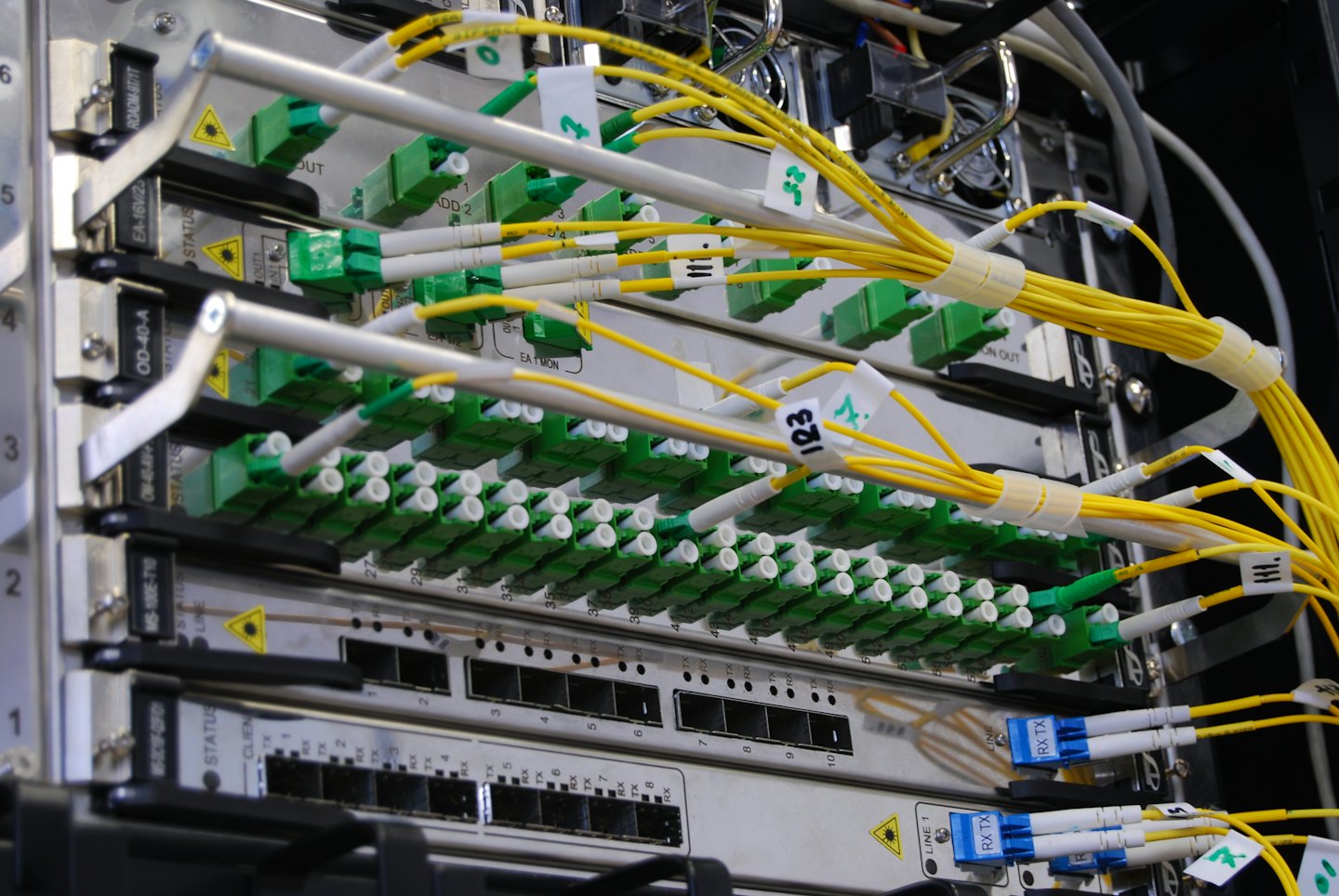 Manos de mujer conectando cables de fibra óptica amarillos a un servidor.